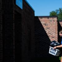 An Alumna carrying a student's items into the dorm.